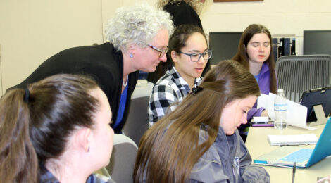 Dean Kim Haverkos, Ph.D., works with Thomas More students in the classroom.