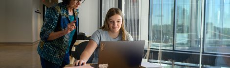 College student working with professor on laptop.