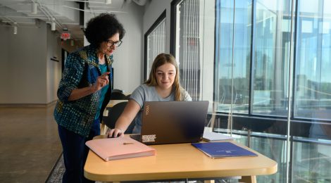 College student working with professor on laptop.