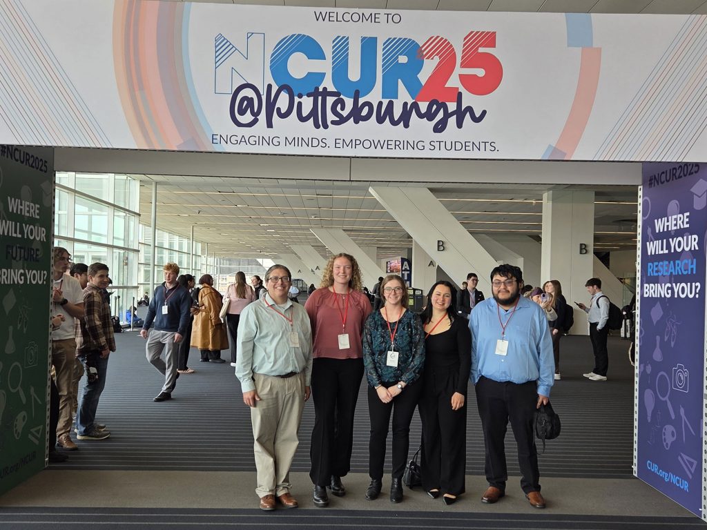 Professor William Wetzel, Ph.D., and Thomas More student researchers Madison Genslinger, Eva Kinwel, Paige Robbins, and Jose Ruiz under the NCUR25 sign.