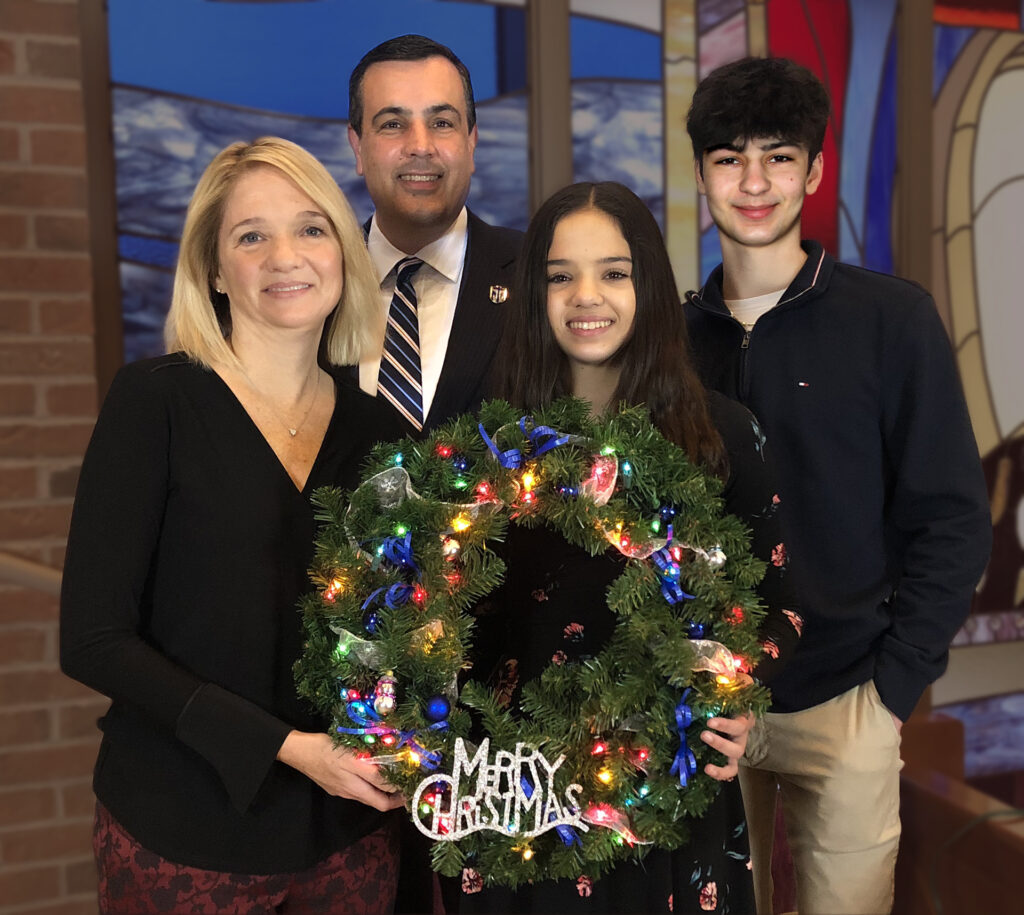 family smiling holding wreath